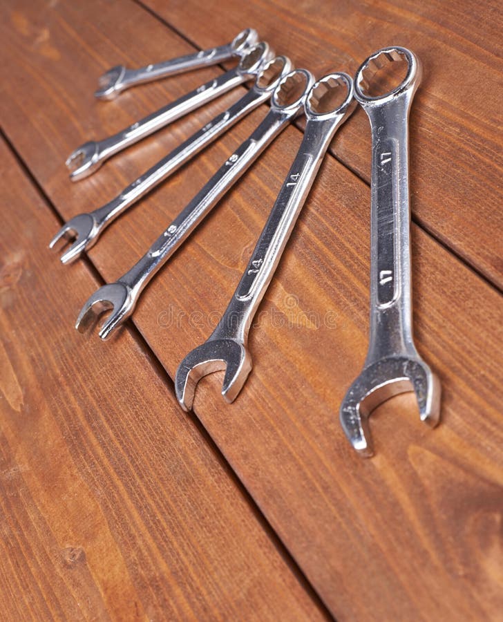 Set of wrenchs chrome metal spanner instruments on wooden surface royalty free stock image
