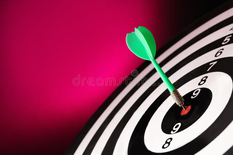 Green arrow hitting target on dart board against magenta background. Space for text. Green arrow hitting target on dart board against magenta background. Space for text