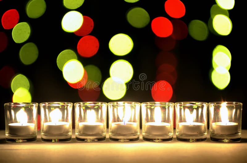 Seven of small glasses that have a small lighting lamps inside arrange in a row with a round yellow and red bokeh of blur light bulb in the back ground. Seven of small glasses that have a small lighting lamps inside arrange in a row with a round yellow and red bokeh of blur light bulb in the back ground