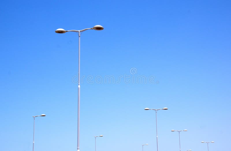 Seven silver street lamps against blue skyline. Seven silver street lamps against blue skyline