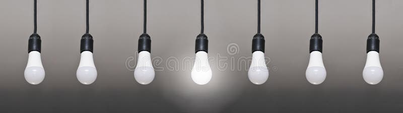 seven LED lamps on wires, only one lamp is lit. on a gray gradient background. seven LED lamps on wires, only one lamp is lit. on a gray gradient background