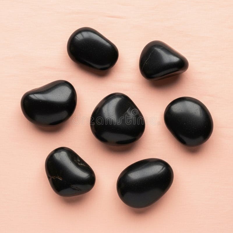 Seven smooth, black stones arranged on a light peach-colored surface royalty free illustration
