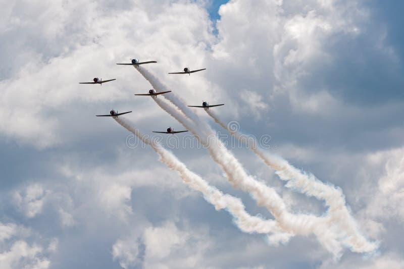 EDEN PRAIRIE, MN - JULY 16, 2016: AT6 Texan planes fly against cloudy sky in close formation at air show. The AT6 Texan was primarily used as trainer aircraft during and after World War II. EDEN PRAIRIE, MN - JULY 16, 2016: AT6 Texan planes fly against cloudy sky in close formation at air show. The AT6 Texan was primarily used as trainer aircraft during and after World War II.