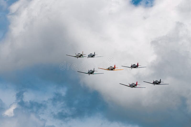 EDEN PRAIRIE, MN - JULY 16 2016: Seven AT6 Texan airplanes fly away in cloudy sky at air show. The AT6 Texan was primarily used as trainer aircraft during and after World War II. EDEN PRAIRIE, MN - JULY 16 2016: Seven AT6 Texan airplanes fly away in cloudy sky at air show. The AT6 Texan was primarily used as trainer aircraft during and after World War II.