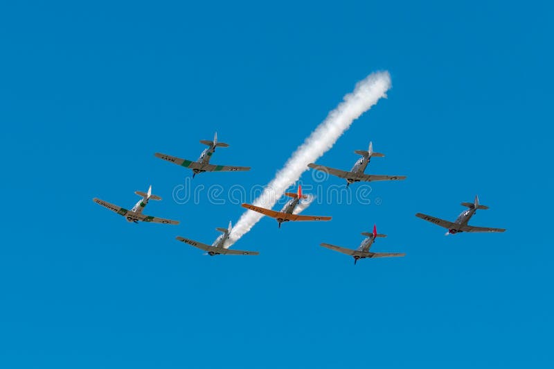 EDEN PRAIRIE, MN - JULY 16 2016: Seven AT6 Texan airplanes fly overhead with one smoke trail at air show. The AT6 Texan was primarily used as trainer aircraft during and after World War II. EDEN PRAIRIE, MN - JULY 16 2016: Seven AT6 Texan airplanes fly overhead with one smoke trail at air show. The AT6 Texan was primarily used as trainer aircraft during and after World War II.