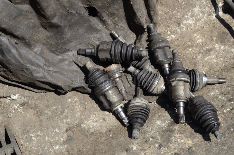 Several auto parts on the ground in a rustic setting. A collage of used auto parts in a barn-like setting with a distressed, weathered look and feel