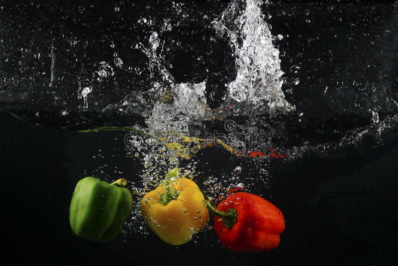 Several Coloured Paprika Falling into Water Splash with Many Bub Stock