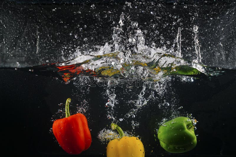 Several Coloured Paprika Falling into Water Splash with Many Bub Stock