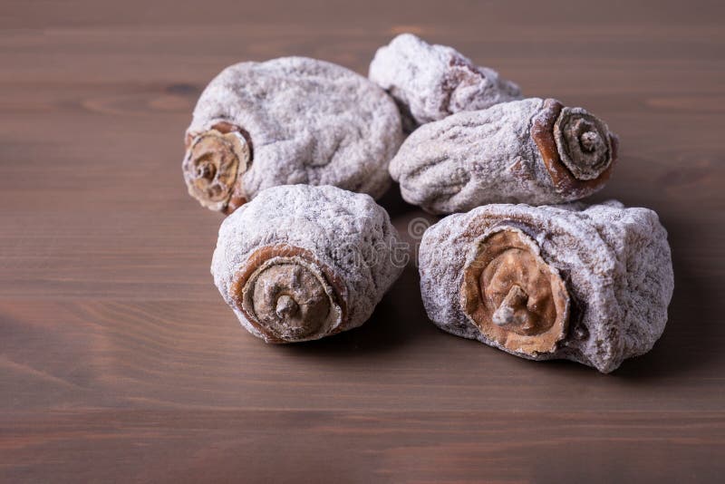 Several dried persimmons on a wooden surface. This is a useful product for diseases of the endocrine and digestive systems, blood vessels, beriberi and anemia. Selective focus. Close-up.