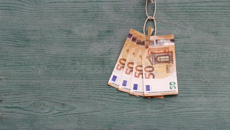 Several fifty-euro notes are hanging on a wooden board