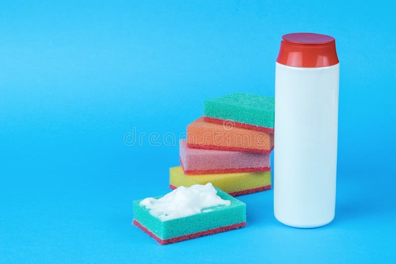 Several multi-colored foam sponges and cleaning agent on a blue background. Minimal concept of washing and cleaning. Multi colored foam sponges stock images, royalty-free photos and pictures