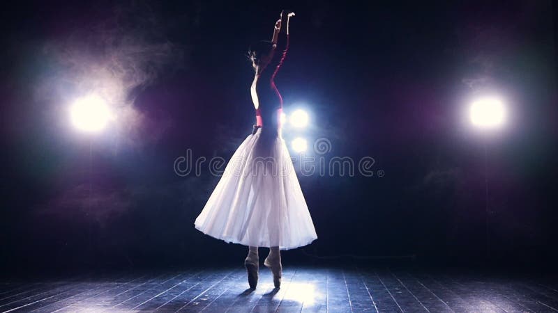 A slowly dancing ballerina in front of spot lights.