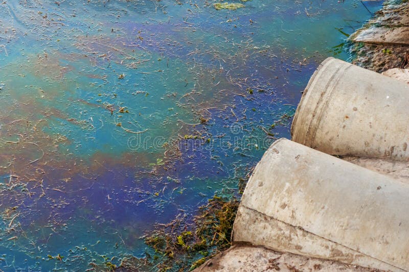 Sewer pipes at shore, stain of oil or fuel on water surface, nature pollution by toxic chemicals, dirty sea concept stock photo Sewer pipes at shore, stain of oil or fuel on water surface, nature pollution by toxic chemicals, dirty sea concept stock photo