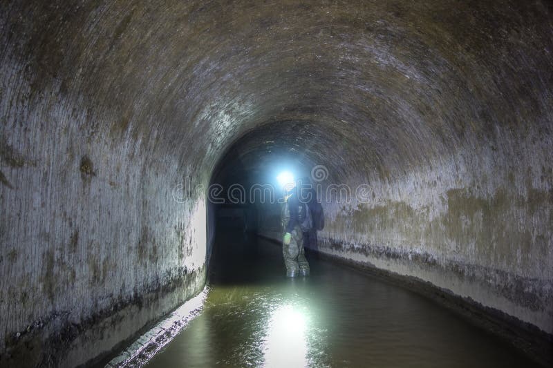 Sewer tunnel worker examines sewer system stock images