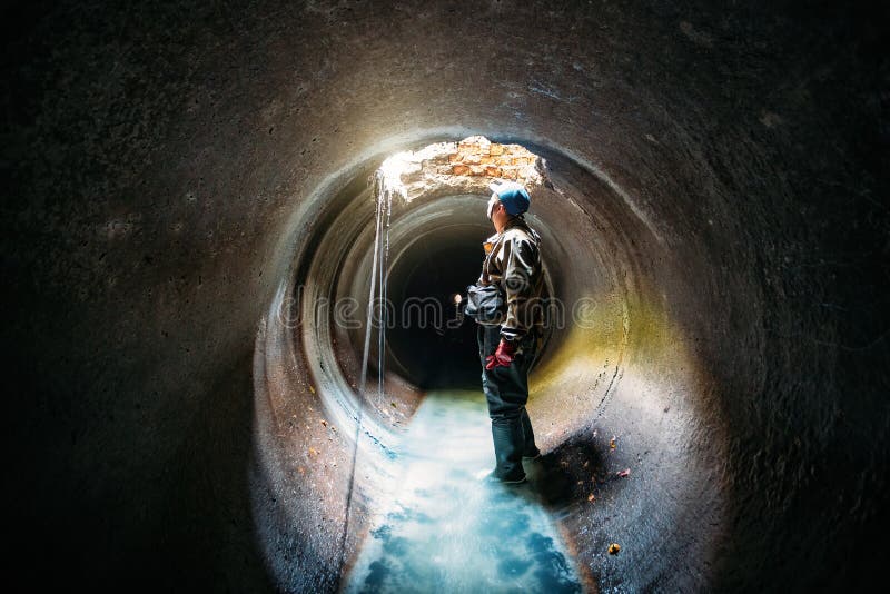 Sewer tunnel worker examines sewer system damage and wastewater leakage royalty free stock photography