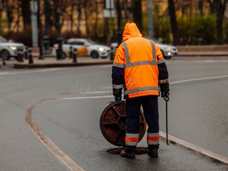 Sewer worker cleaning manhole and unblocking sewers the road stock photos