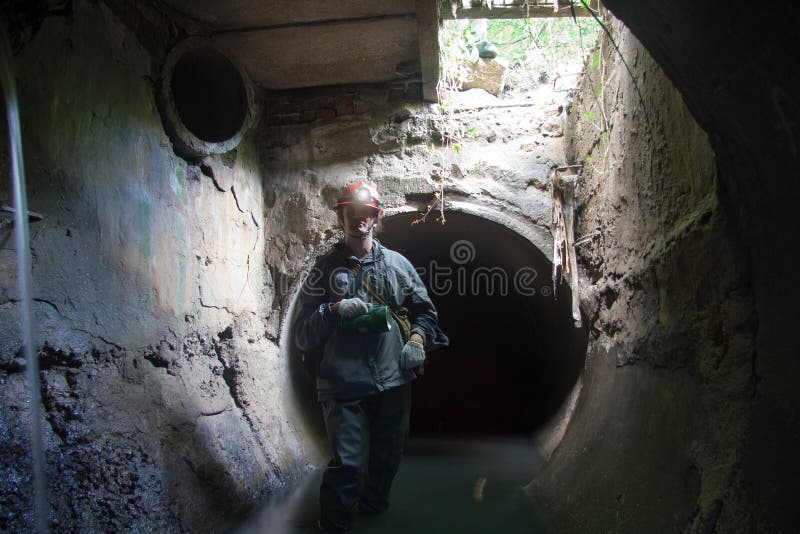 Sewer worker in underground flooded sewage collector stock image