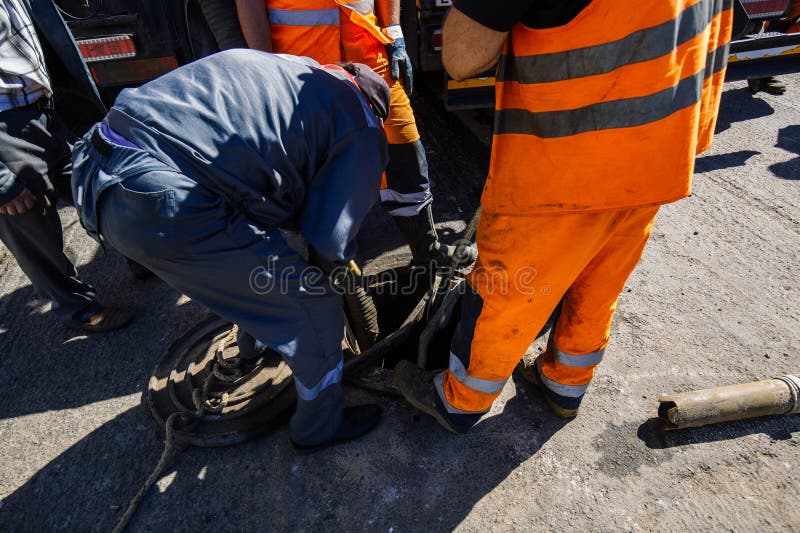 Sewer workers cleaning manhole and unblocking sewers stock image