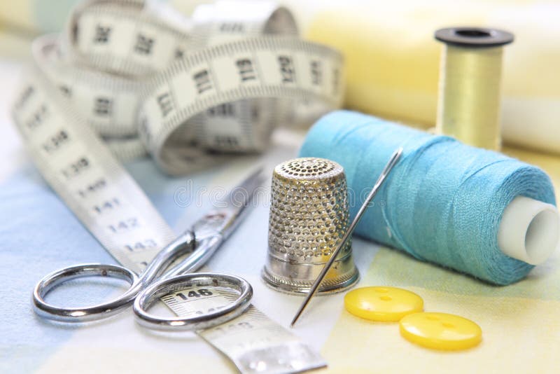Sewing accessories with blue and yellow threads, tape measure and scissors on fabric background royalty free stock photography Sewing accessories with blue and yellow threads, tape measure and scissors on fabric background royalty free stock photography