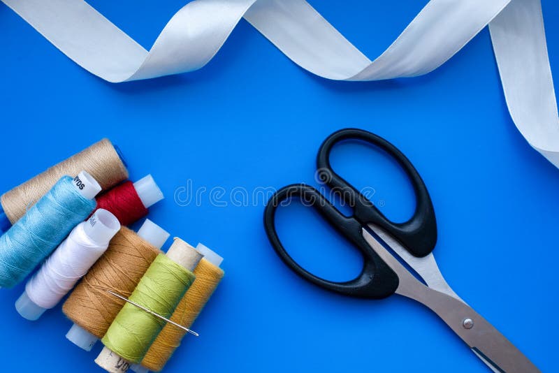 Sewing Accessories Scissors, Thread, Ribbons on a Blue Background, Soft Focus Stock Image