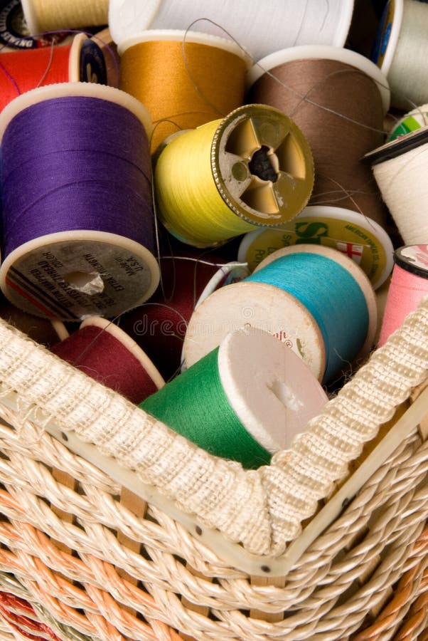 The concept of sewing and embroidery is highlighted by colorful spools of thread in a sewing basket. The concept of sewing and embroidery is highlighted by colorful spools of thread in a sewing basket