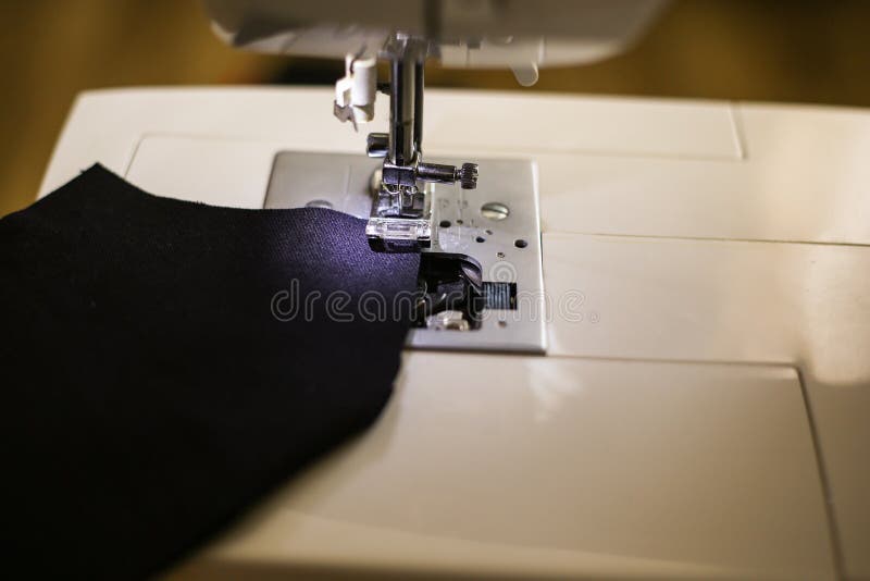 Sewing machine and black pattern fabric face mask. Sewing a mask on a typewriter during a pandemic