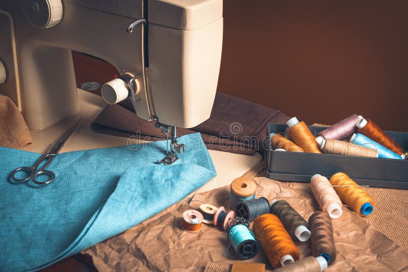 Sewing machine, threads of fabric on a brown tinted background. royalty free stock image