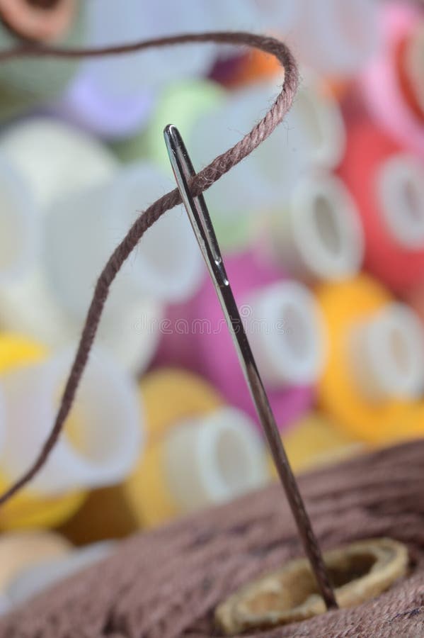 A Sewing Needle with Brown Thread through the Eye of the Needle. Macro Stock Photo Image of