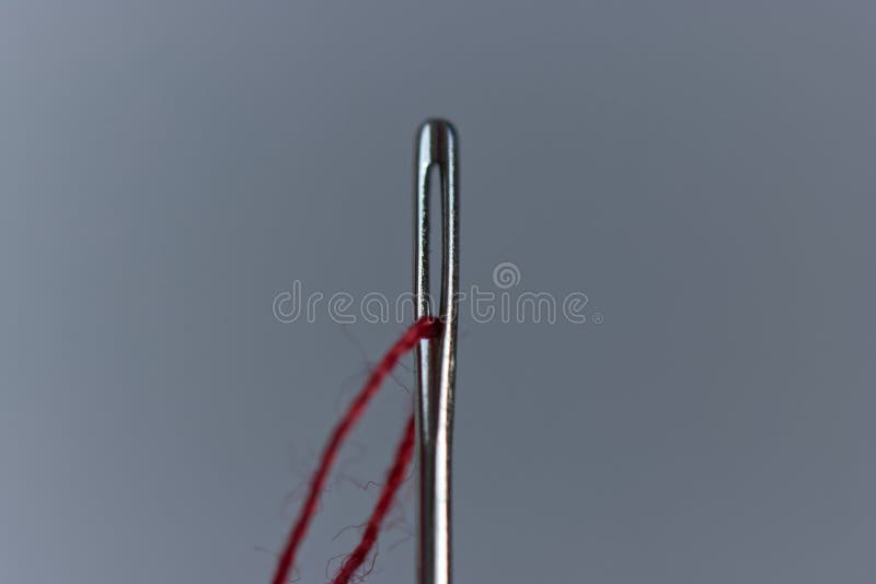 Sewing Needle Eye and Red Thread. Macro Photo with Extreme Close Up