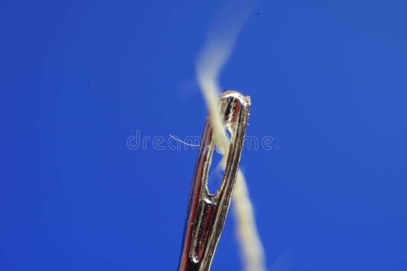 Sewing Needle with a Yellow Thread Passing through the Groove on a Blue