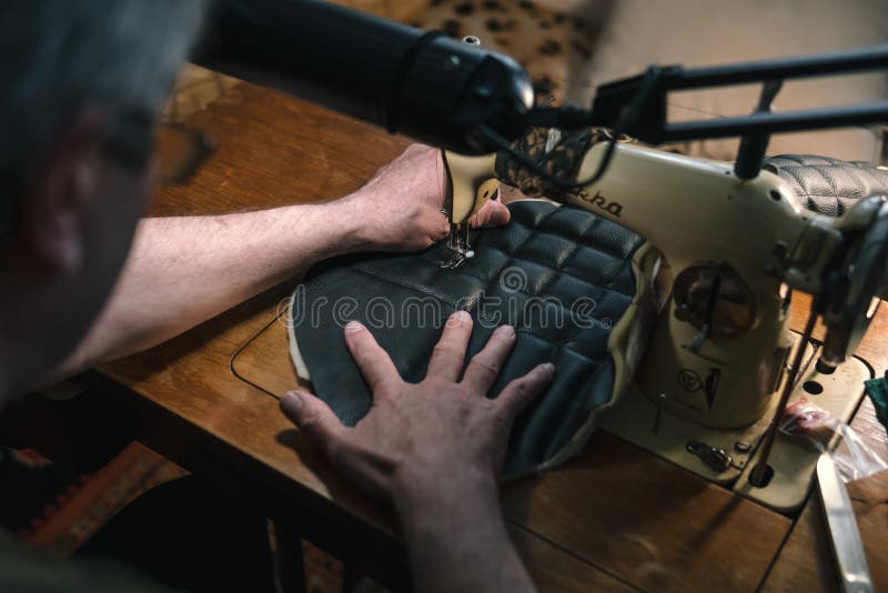 Sewing process of the leather belt. old Man`s hands behind sewing. Leather workshop. textile vintage sewing industrial stock photos Sewing process of the leather belt. old Man`s hands behind sewing. Leather workshop. textile vintage sewing industrial stock photos