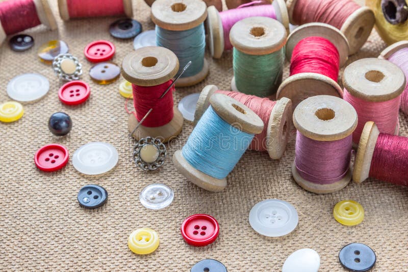Sewing tools many different colorful thread, needle, many different buttons on wooden background. royalty free stock photo