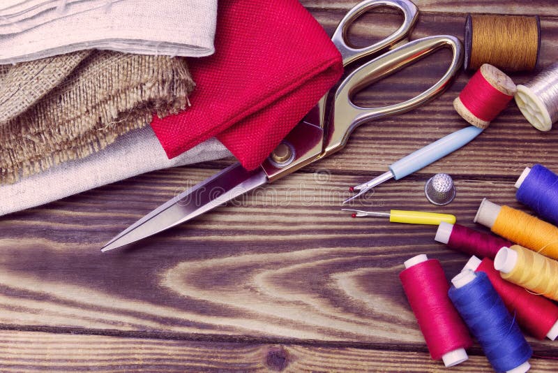 Sewing Tools, Multicoloured Fabric and Threads on a Wooden Background