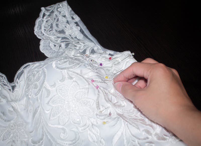 Sewing Wedding Dress, Hand Seamstress Holding a Needle Over the Fabric