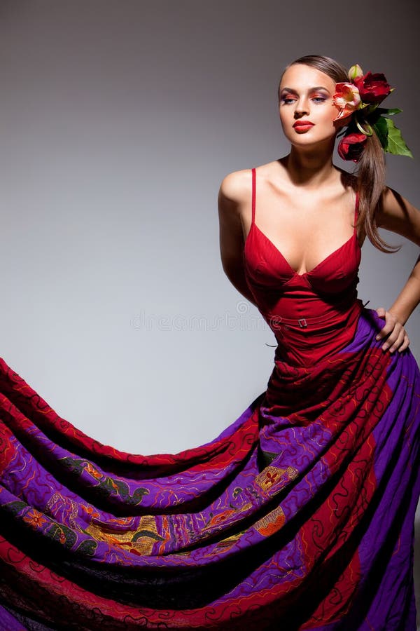 Sexual girl in red dress with flowers in her hair in studio