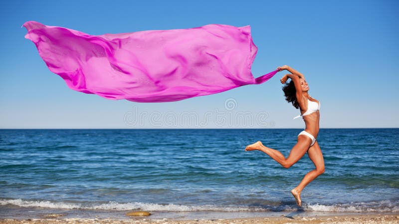 athletic brunette jumping on the beach.