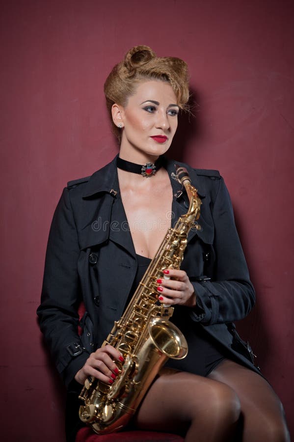 attractive woman with saxophone posing on red background. Young sensual blonde playing sax. Musical instrument, jazz stock image attractive woman with saxophone posing on red background. Young sensual blonde playing sax. Musical instrument, jazz stock image