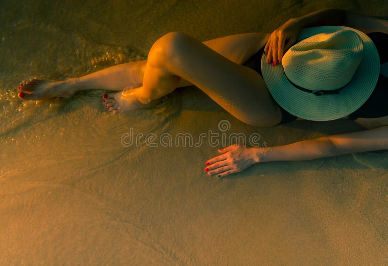 Sexy Aziatische vrouw die met hoed op zandstrand tijdens zonsondergang liggen Het zwarte het zwempak van de vrouwenslijtage ontsp royalty-vrije stock fotografie Sexy Aziatische vrouw die met hoed op zandstrand tijdens zonsondergang liggen Het zwarte het zwempak van de vrouwenslijtage ontsp royalty-vrije stock fotografie