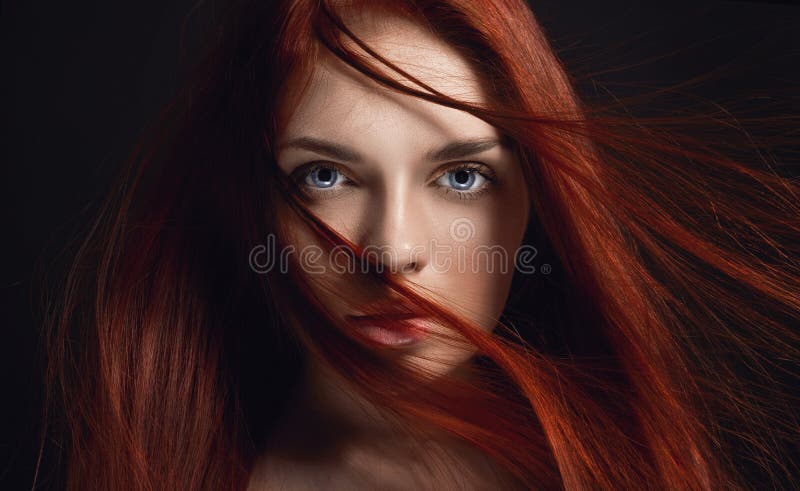 Beautiful redhead girl with long hair. Perfect woman portrait on black background. Gorgeous hair and deep eyes Natural beauty
