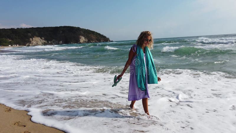 Sexy blonde vrouw die op het strand loopt