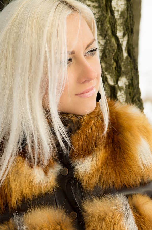 blonde girl lean on a tree winter. blonde girl lean on a tree winter