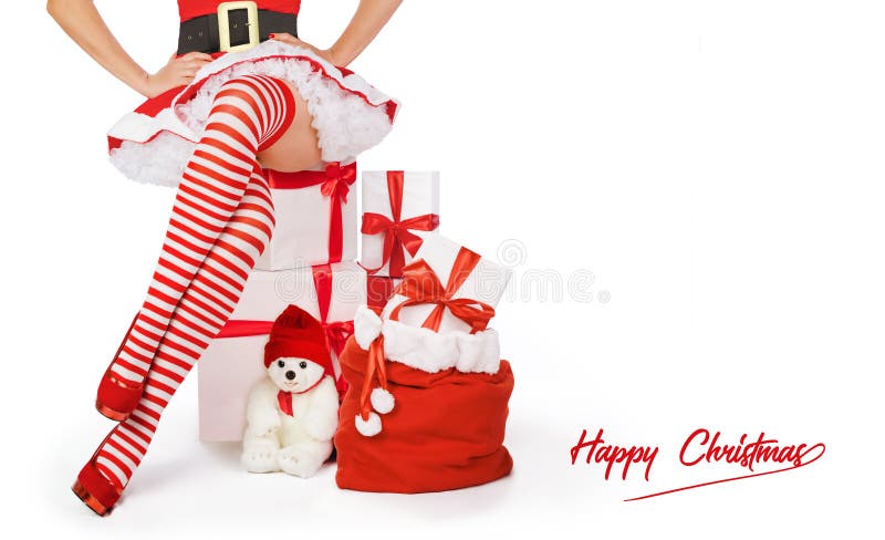 Sexy Christmas woman. Beautiful Mrs santa claus legs in striped stockings and high heels next to xmas gifts and happy Christmas