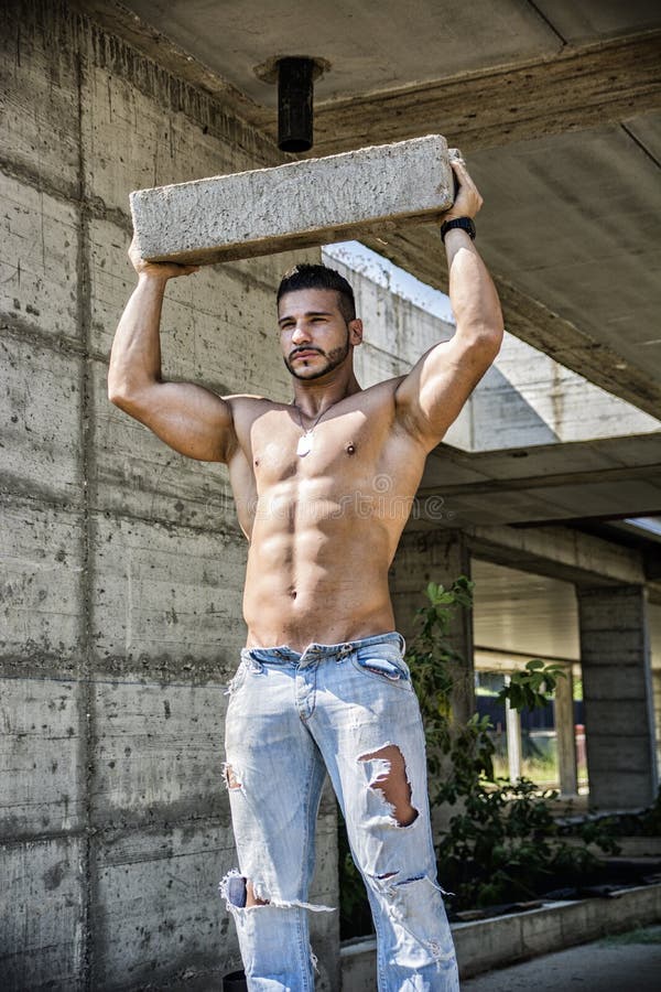 Construction worker shirtless showing muscular body, holding big concrete b...