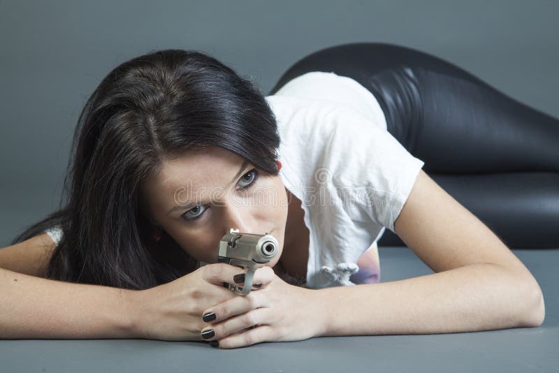 girl lying down aiming gun in fashion style. girl lying down aiming gun in fashion style