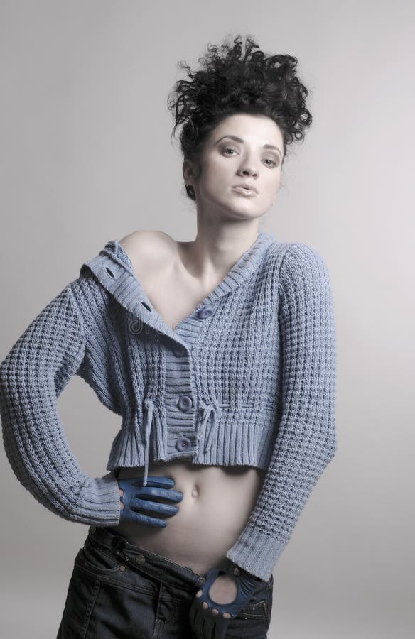 Studio photo young black-haired girl woman in a blue knitted sweater, denim skirt and blue leather gloves on his hands, his eyes set on you. Studio photo young black-haired girl woman in a blue knitted sweater, denim skirt and blue leather gloves on his hands, his eyes set on you.