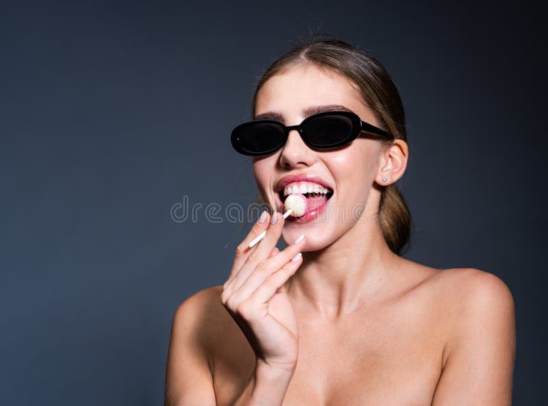 Sexy girl with lollipop. Fashion portrait young woman and lollipop is having fun over gray background.