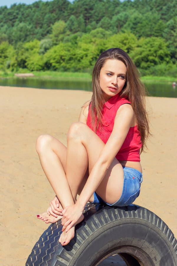 girl with long dark hair sitting in shorts on the beach on the wheel on a Sunny day