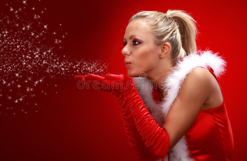 girl in santa cloth blowing snow from hands.