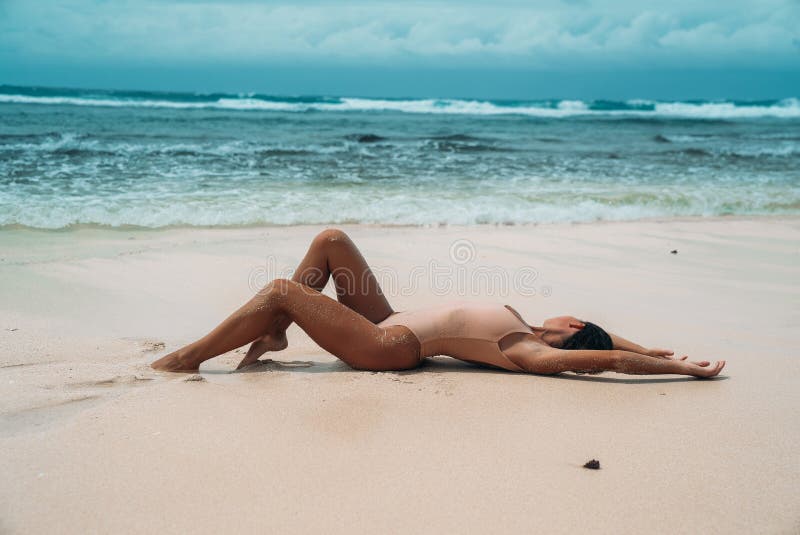 Girl with a Sports Figure Lies on White Sand Near the Ocean hq nude image