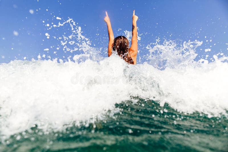 girl swim sea waves hands up splash back view